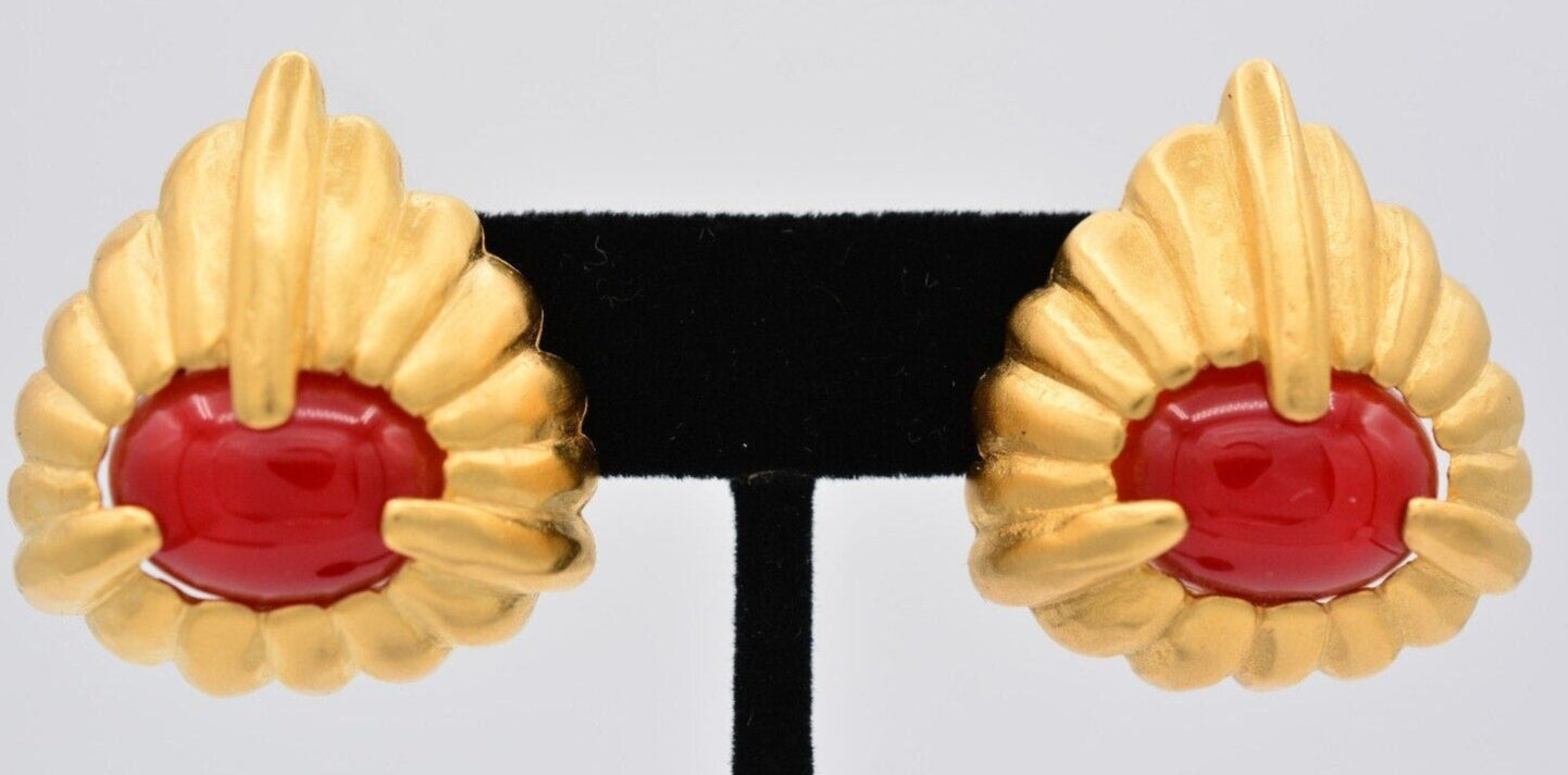 Close view of a pair of brushed gold vintage Givenchy earrings with bright red cabochons in the center on a black velvet stand