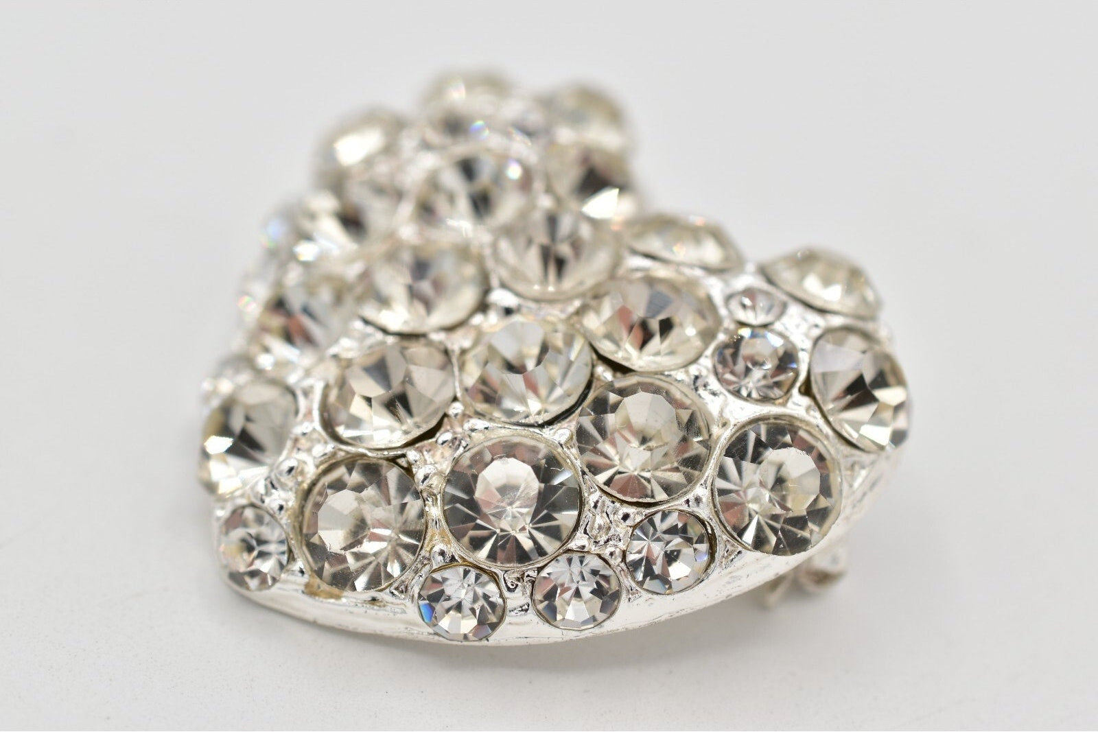 Heart-shaped decorative item with clear rhinestones on a light gray background
