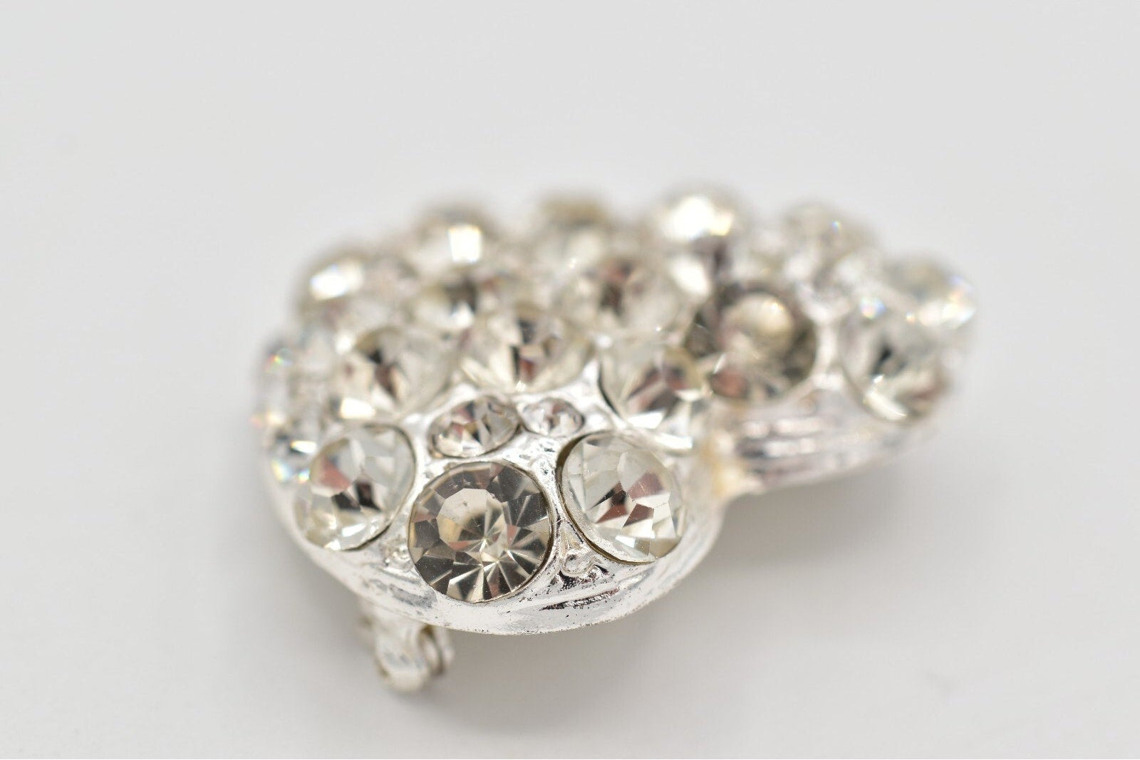 Heart-shaped jewelry piece with clear gemstones on a light gray background