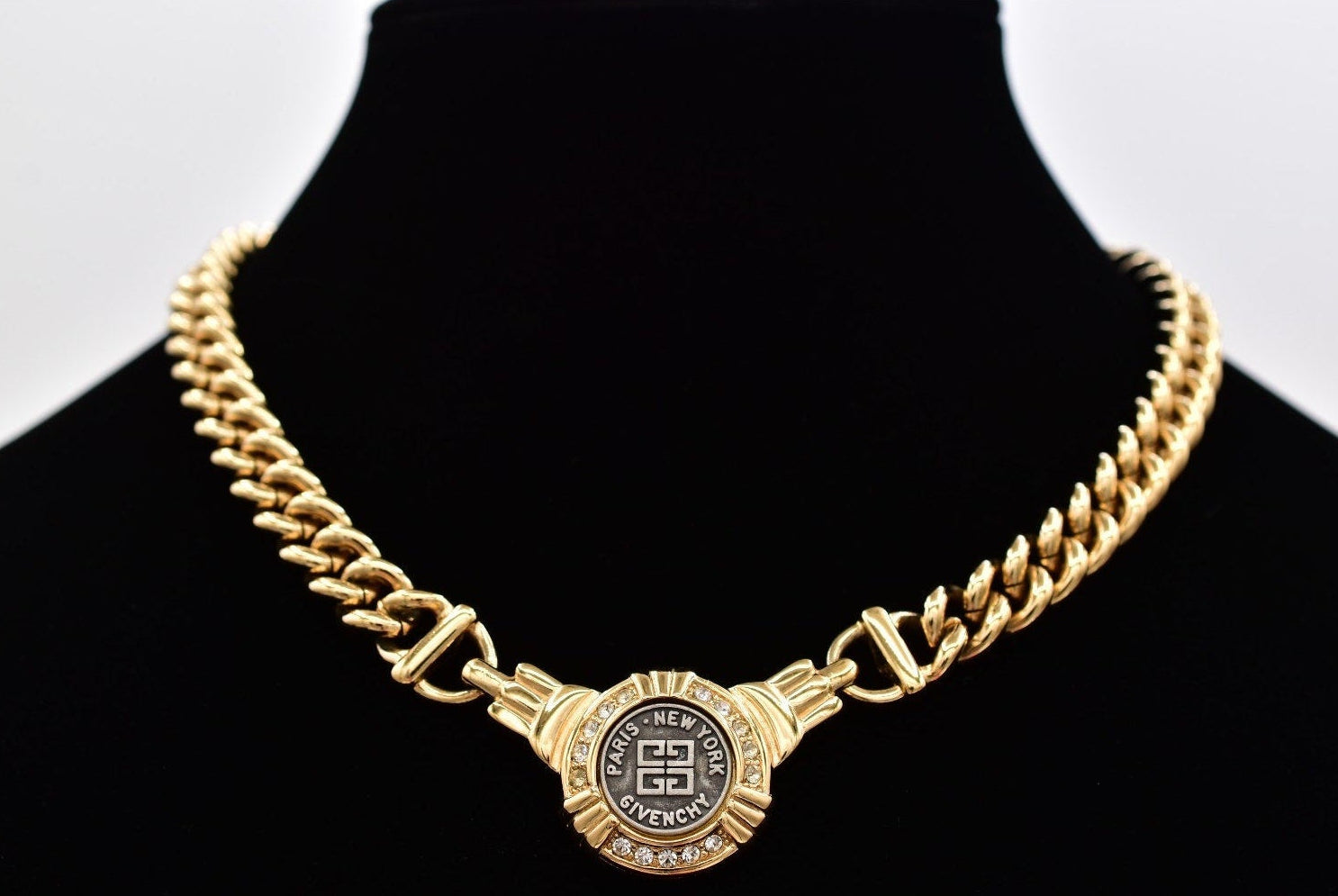 Gold Givenchy coin necklace on a black mannequin against a white background