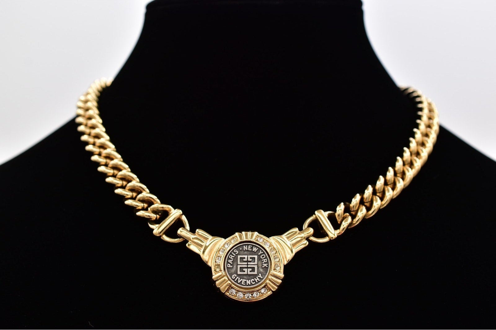 Gold chain necklace with Givenchy clasp on a black mannequin against a white background