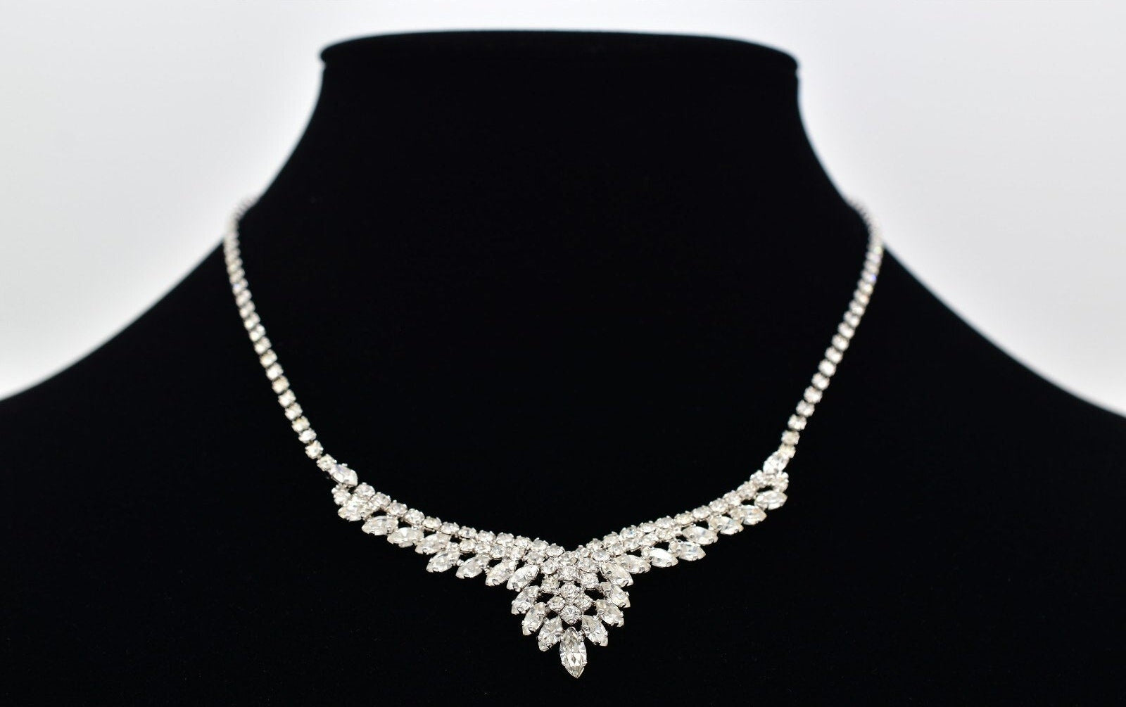 Silver necklace with round and marquise rhinestones on a black mannequin bust with a white background