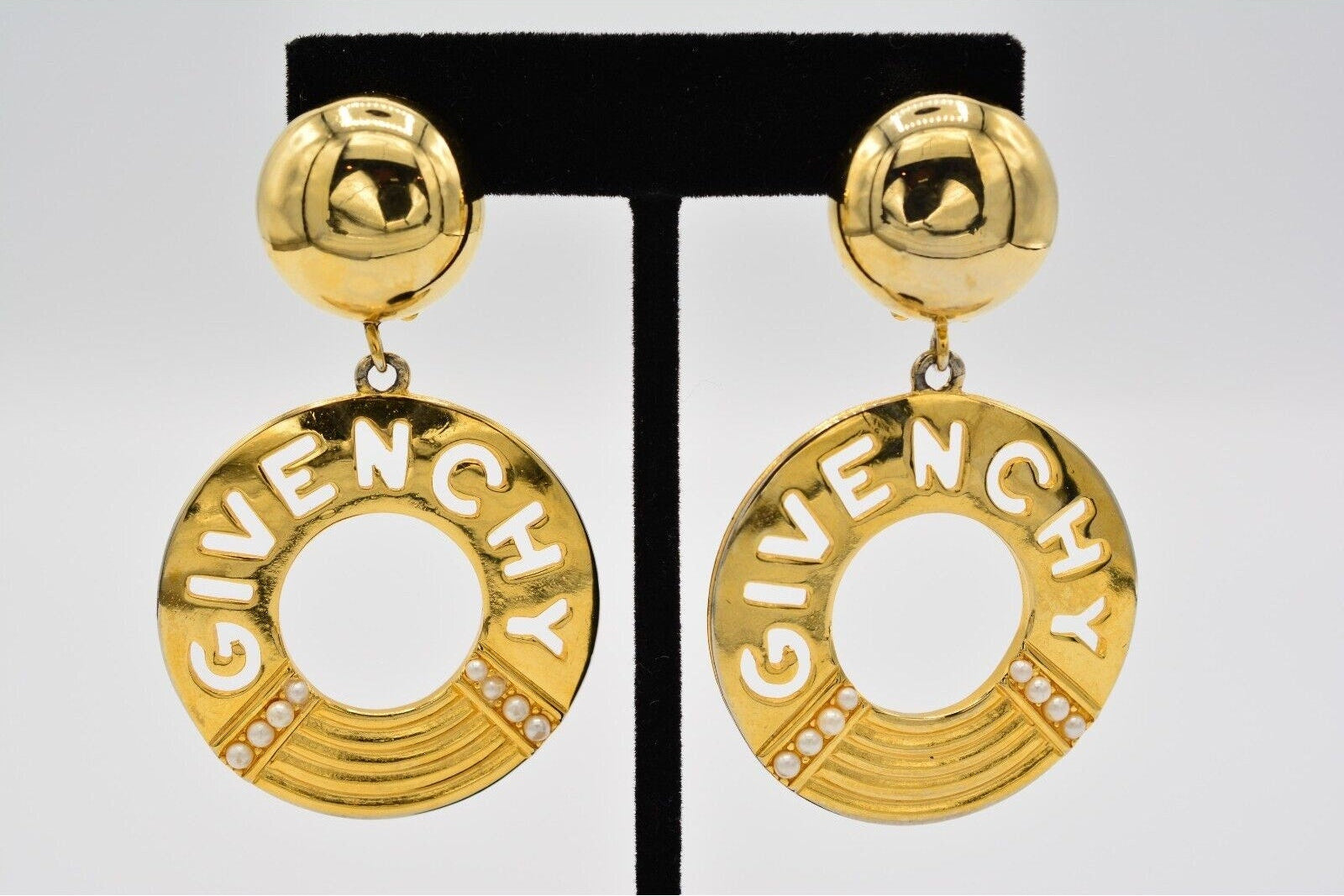Gold Givenchy earrings on a black and white display card.