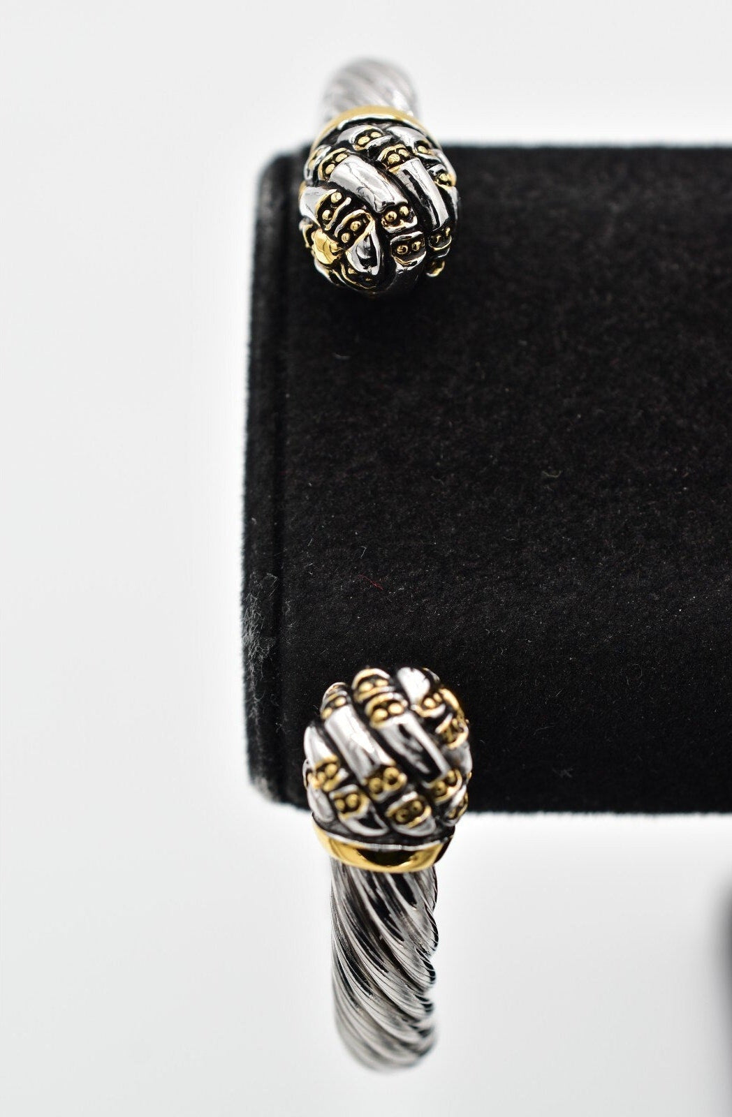 Pair of silver and gold earrings on a black card with a white background