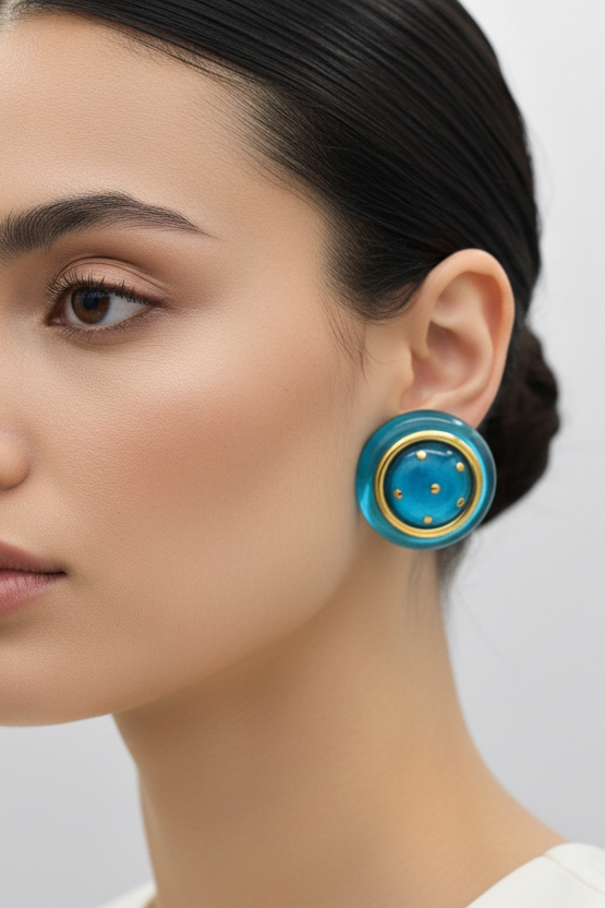 Close-up of a woman wearing a blue earring with gold accents on a plain background
