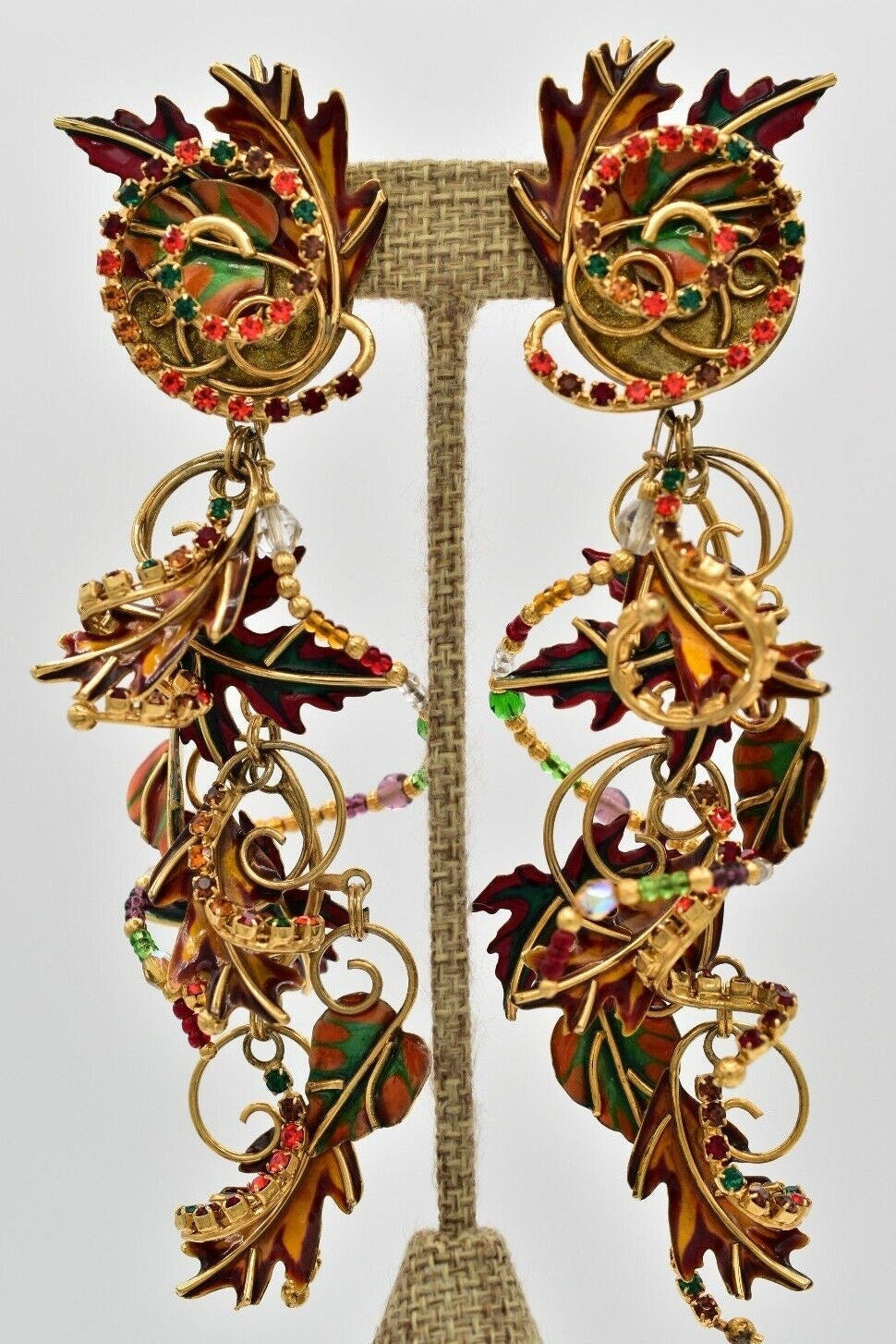A pair of vintage clip-on earrings featuring a design of autumn foliage with gold, red, and green colors.