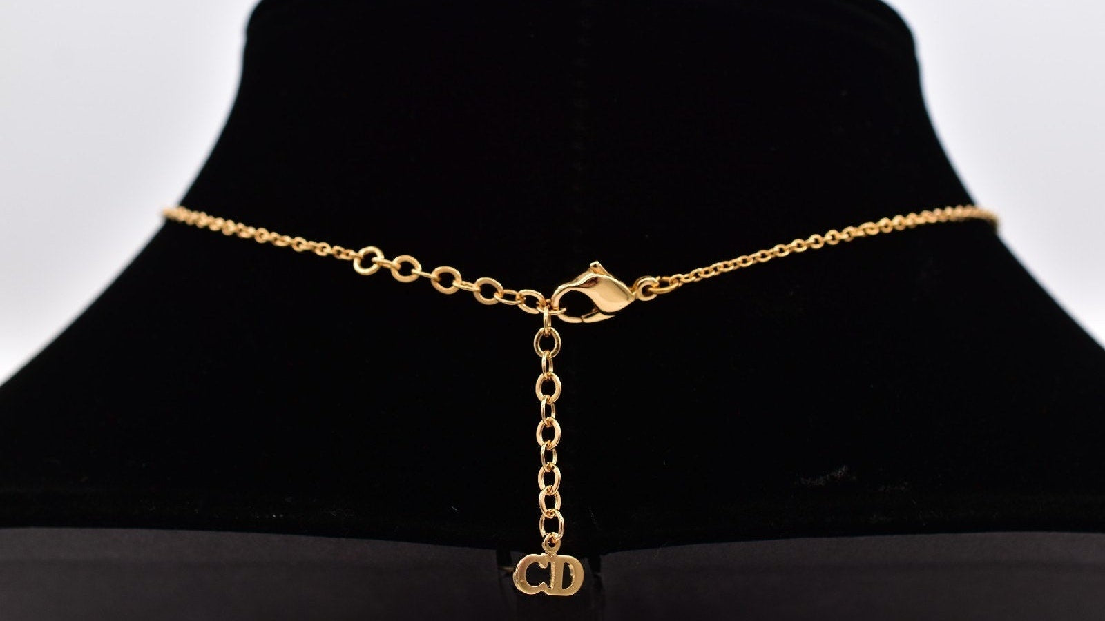 Christian Dior CD hangtag with a clasp on a black mannequin bust against a white background