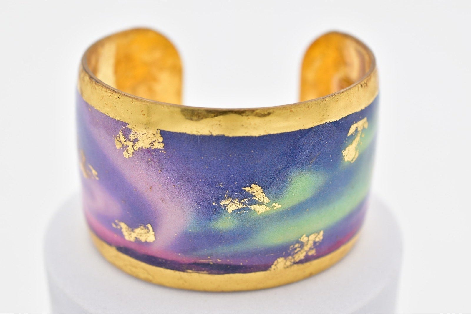 Cuff bracelet with gold accents and a colorful design on a white background
