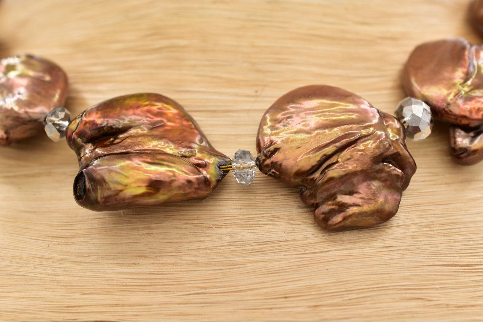 Close-up of a necklace with large, textured beads on a wooden surface