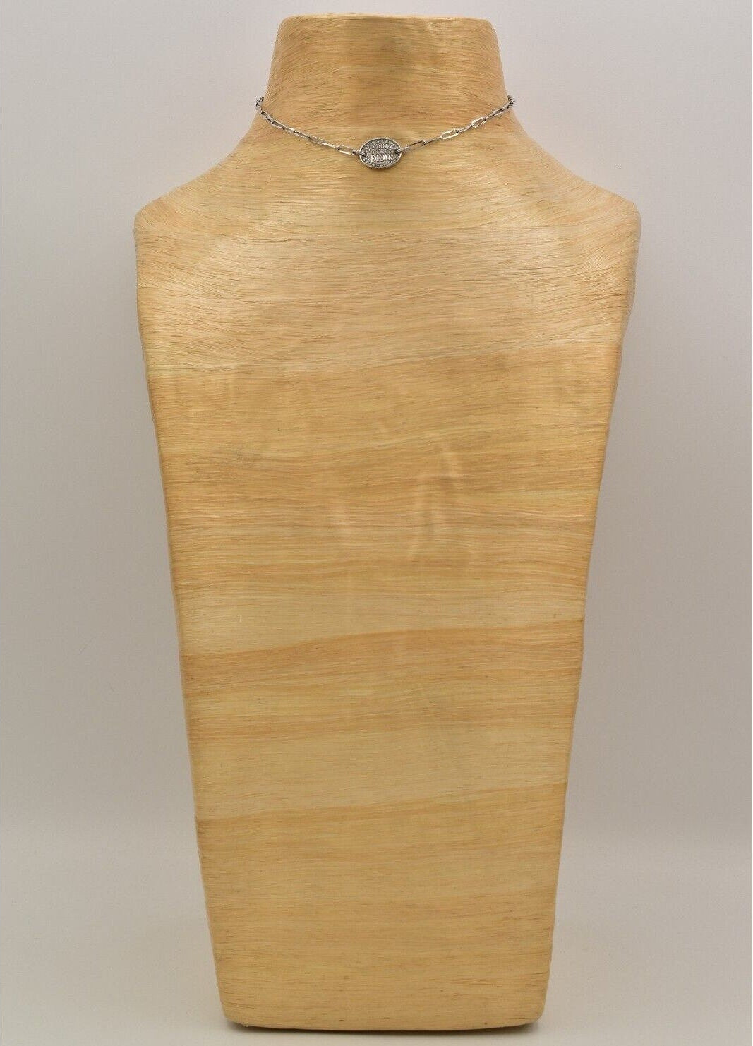 Vintage Dior J'Adore silver chain necklace with a round pendant on a wooden mannequin bust.