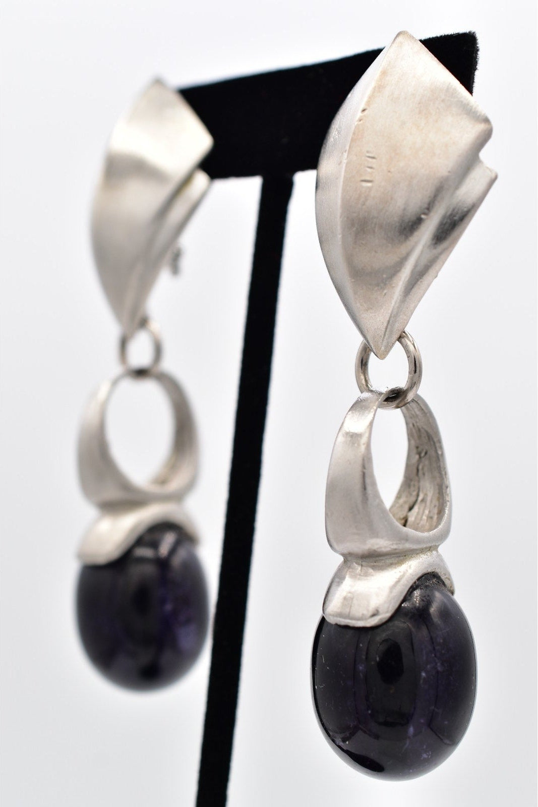 Silver earrings with black beads on a white background