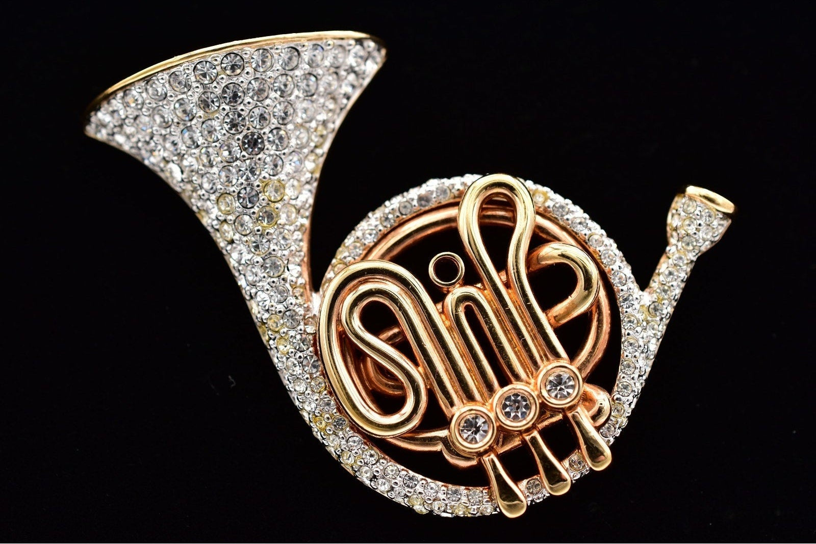 Gold and silver cornet-shaped brooch on a black background