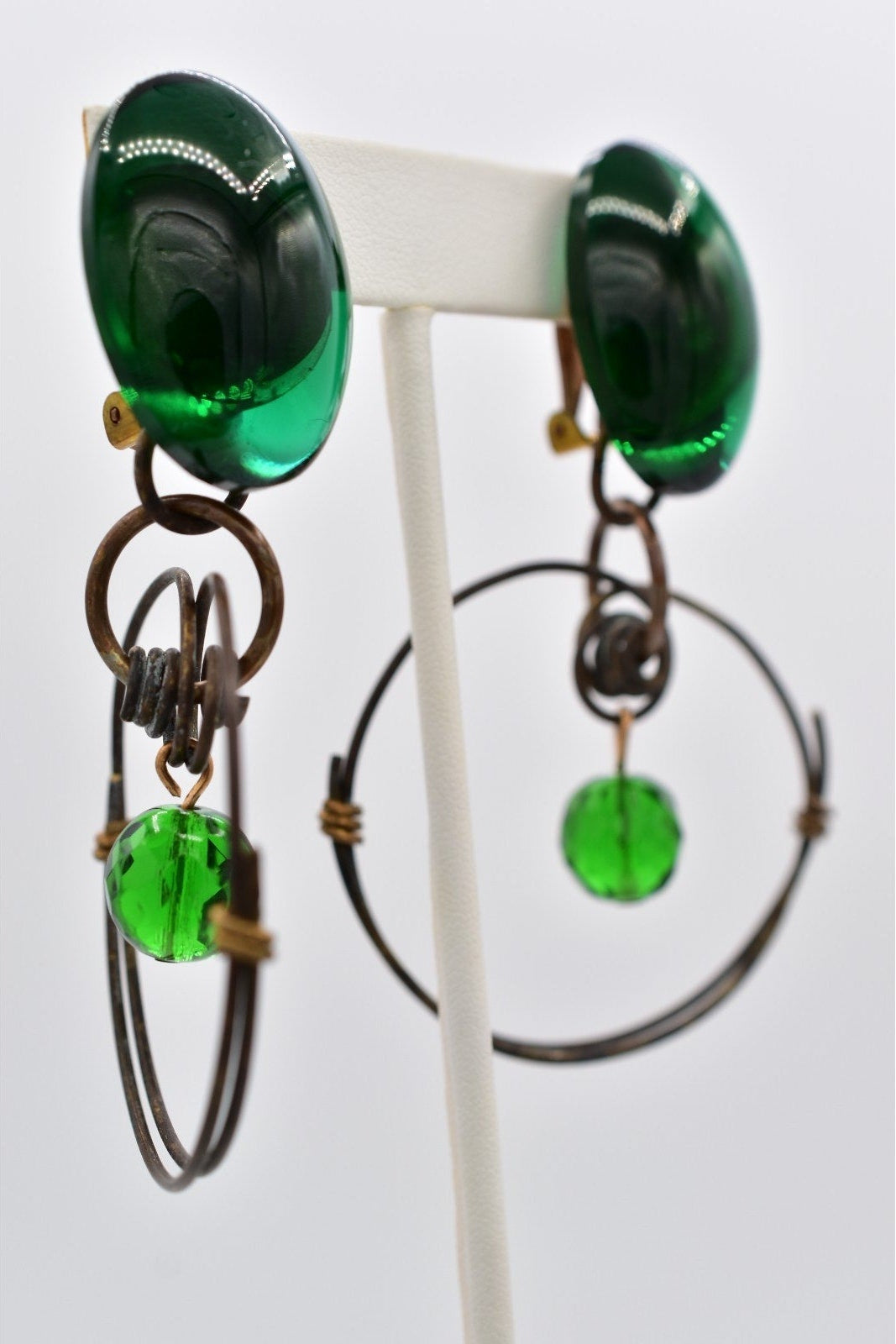 Green glass earrings on a white stand with a white background