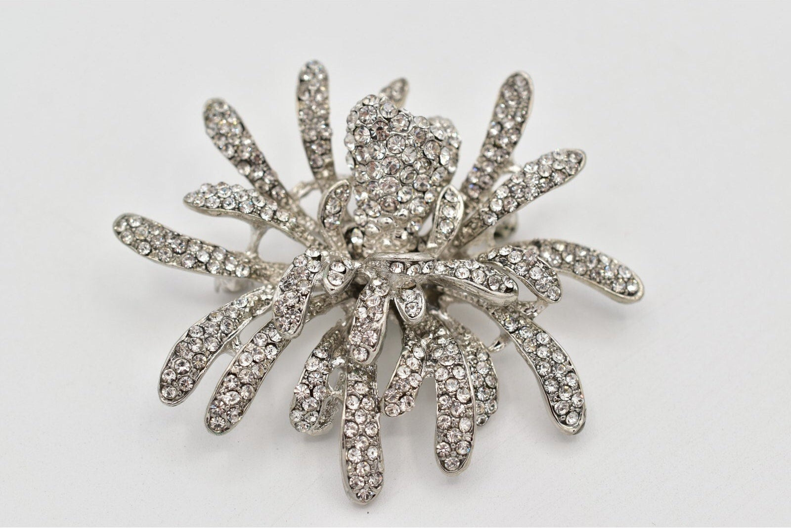 Silver starburst brooch with rhinestones on a white background