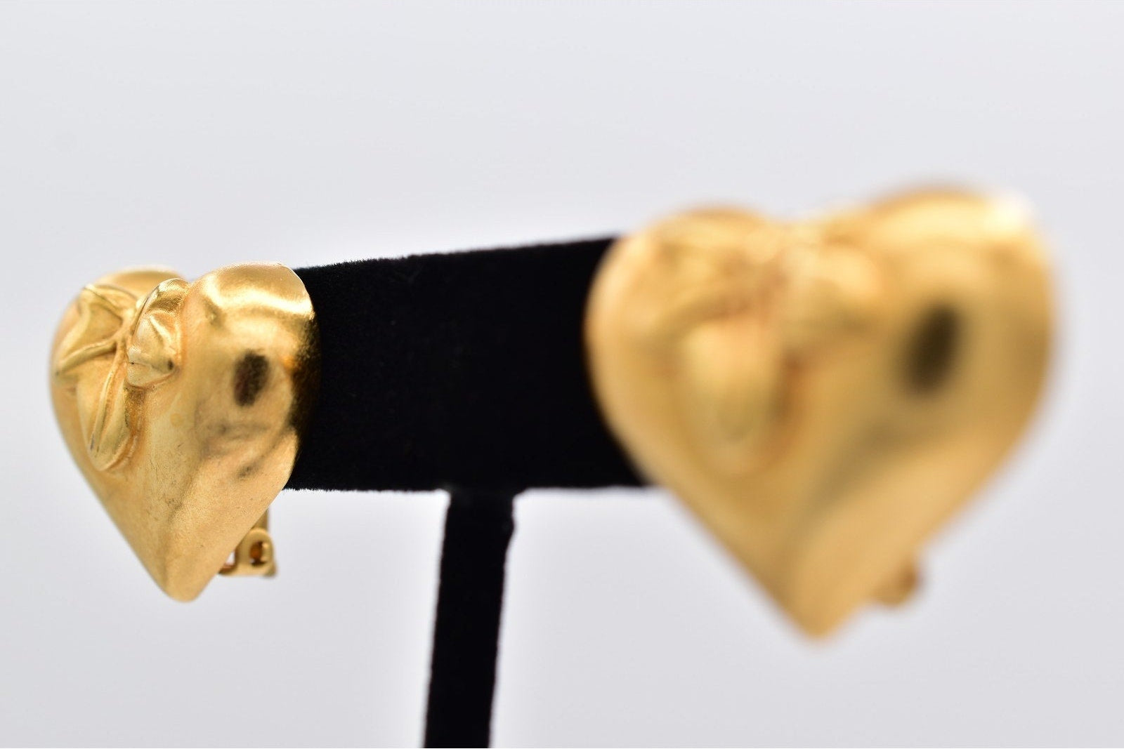 Gold heart-shaped earrings on a black and white card with a light gray background