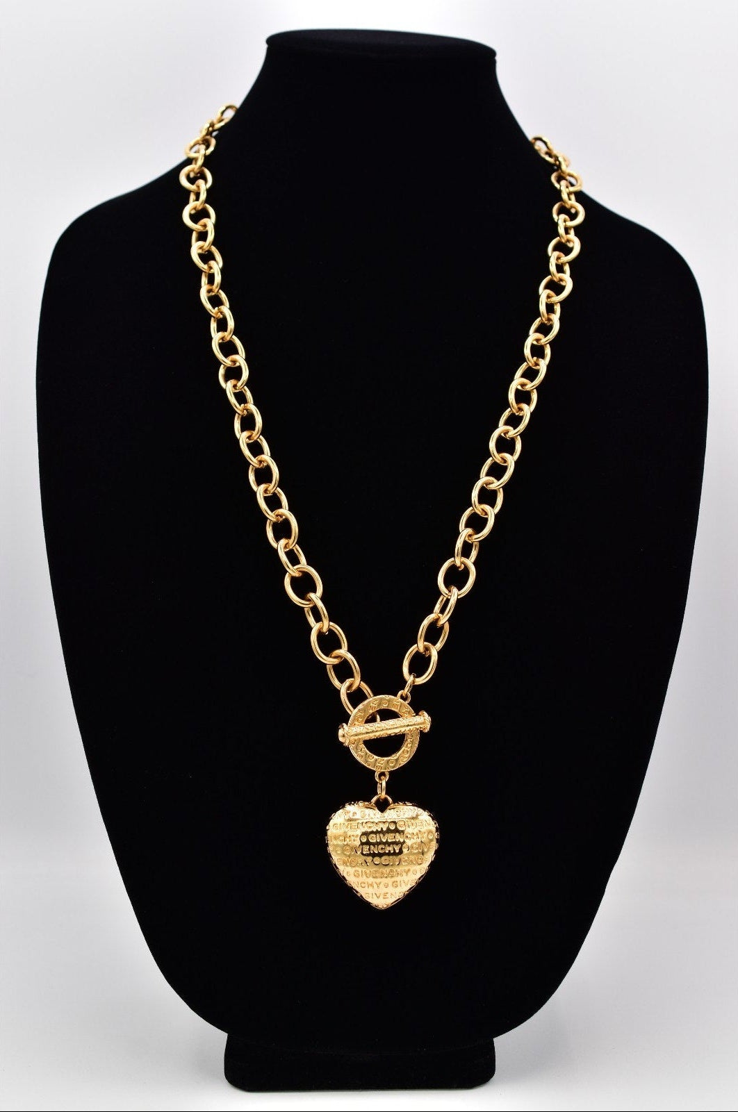 Gold chain necklace with a heart-shaped pendant on a black mannequin bust.