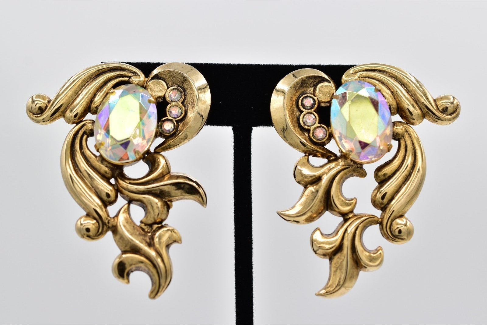 Gold earrings with intricate designs and colorful gemstones on a white background