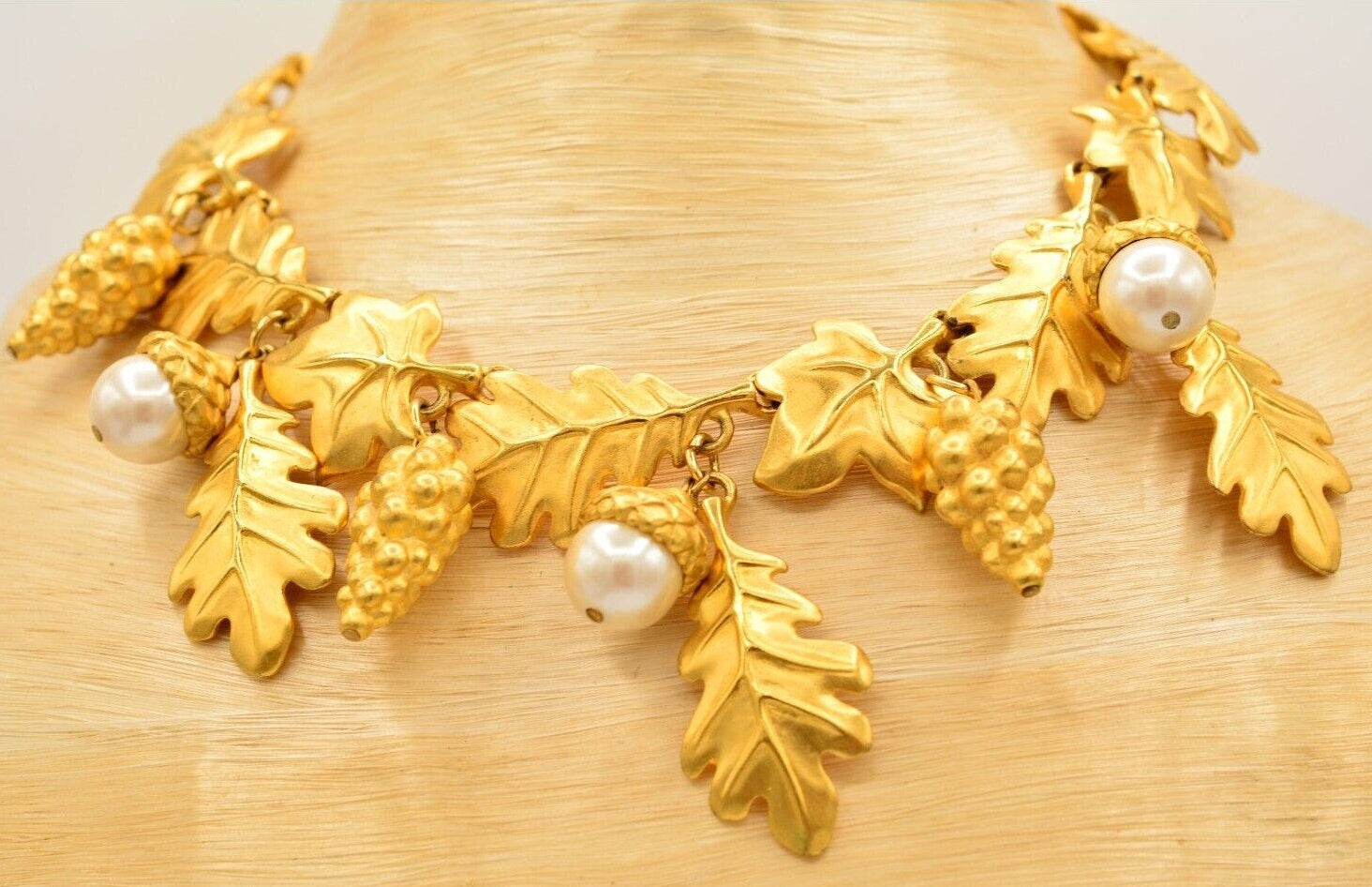 Vintage gold Givenchy necklace with leaf and pearl designs on a beige bust