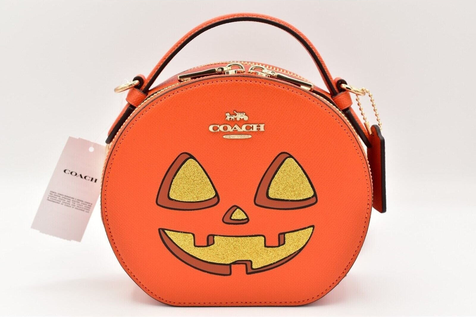 Orange Coach bag with pumpkin face design on a white background