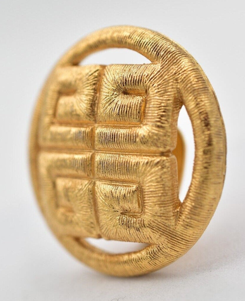 Gold earring with textured design on a light gray background