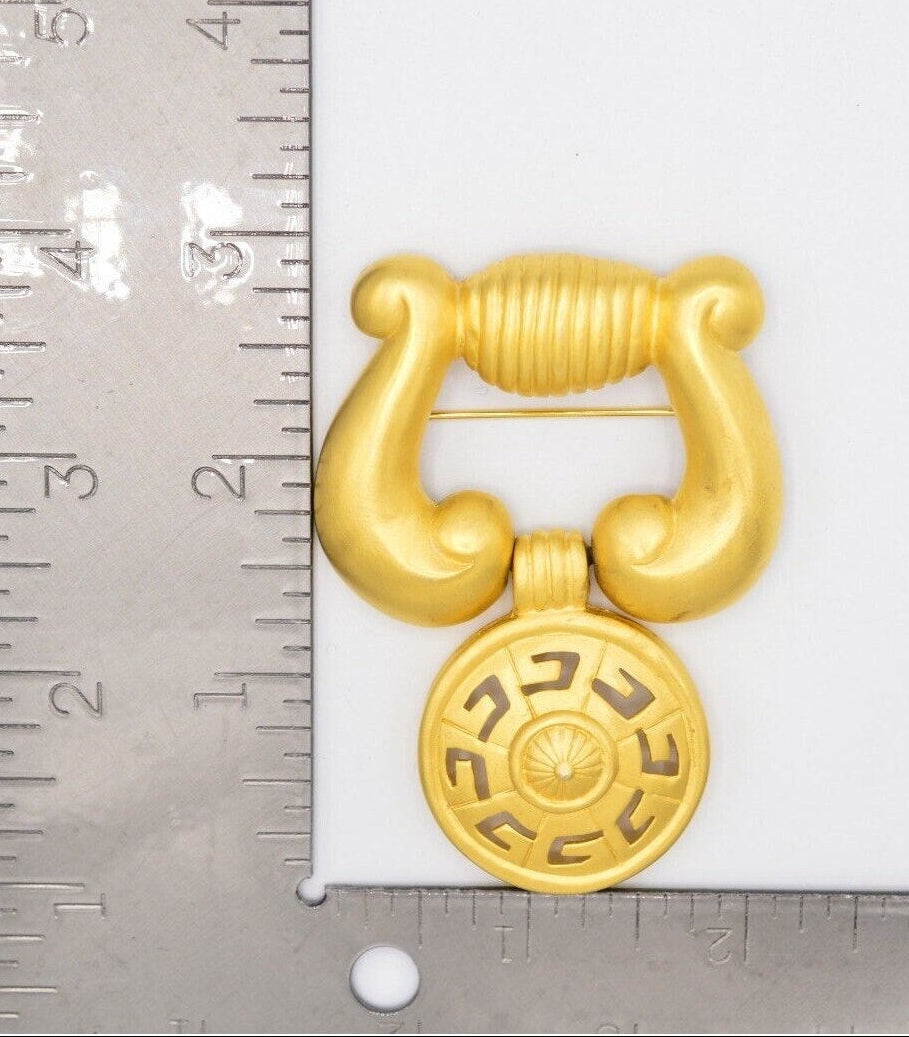 Vintage Givenchy gold tone door knocker brooch with ruler for scale.
