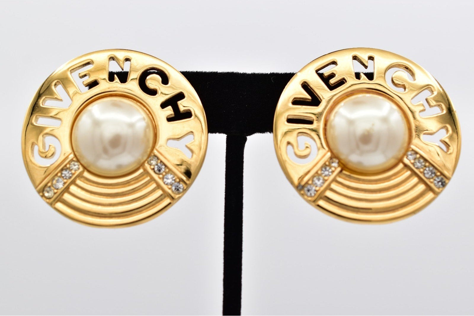 Gold earrings with pearl center and 'GIVENCHY' branding on a white background