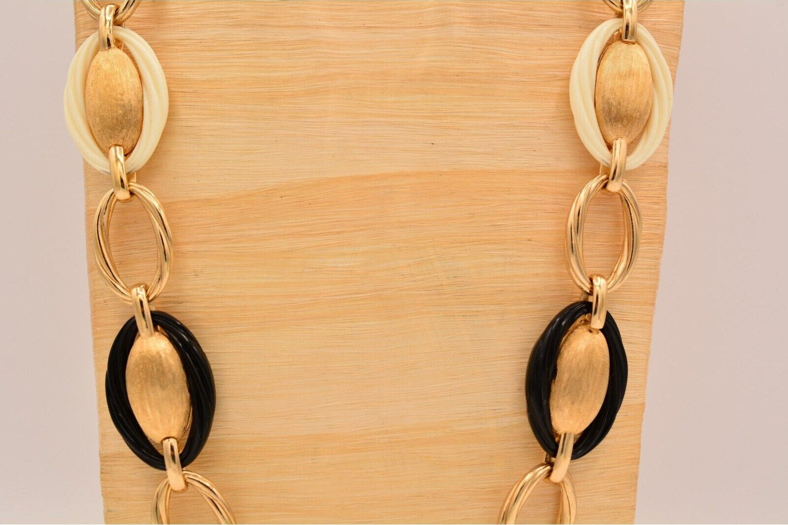 Gold and black chain necklace on a wooden stand
