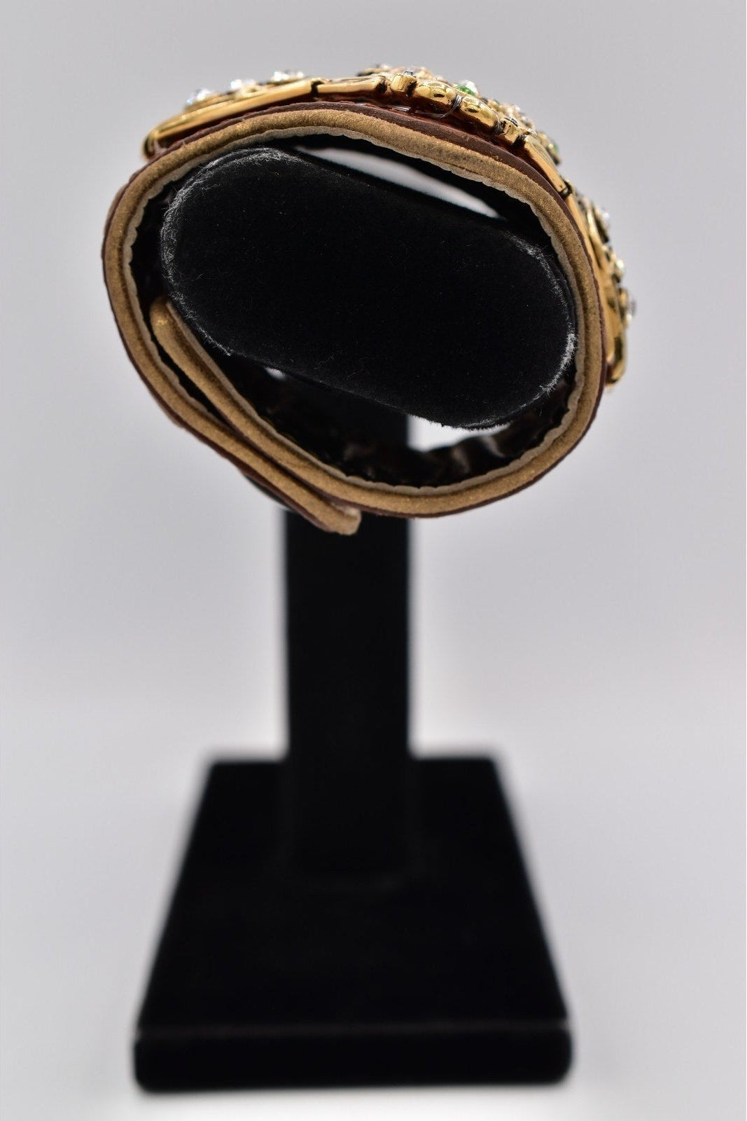 Black stone with gold setting on a black stand against a gray background