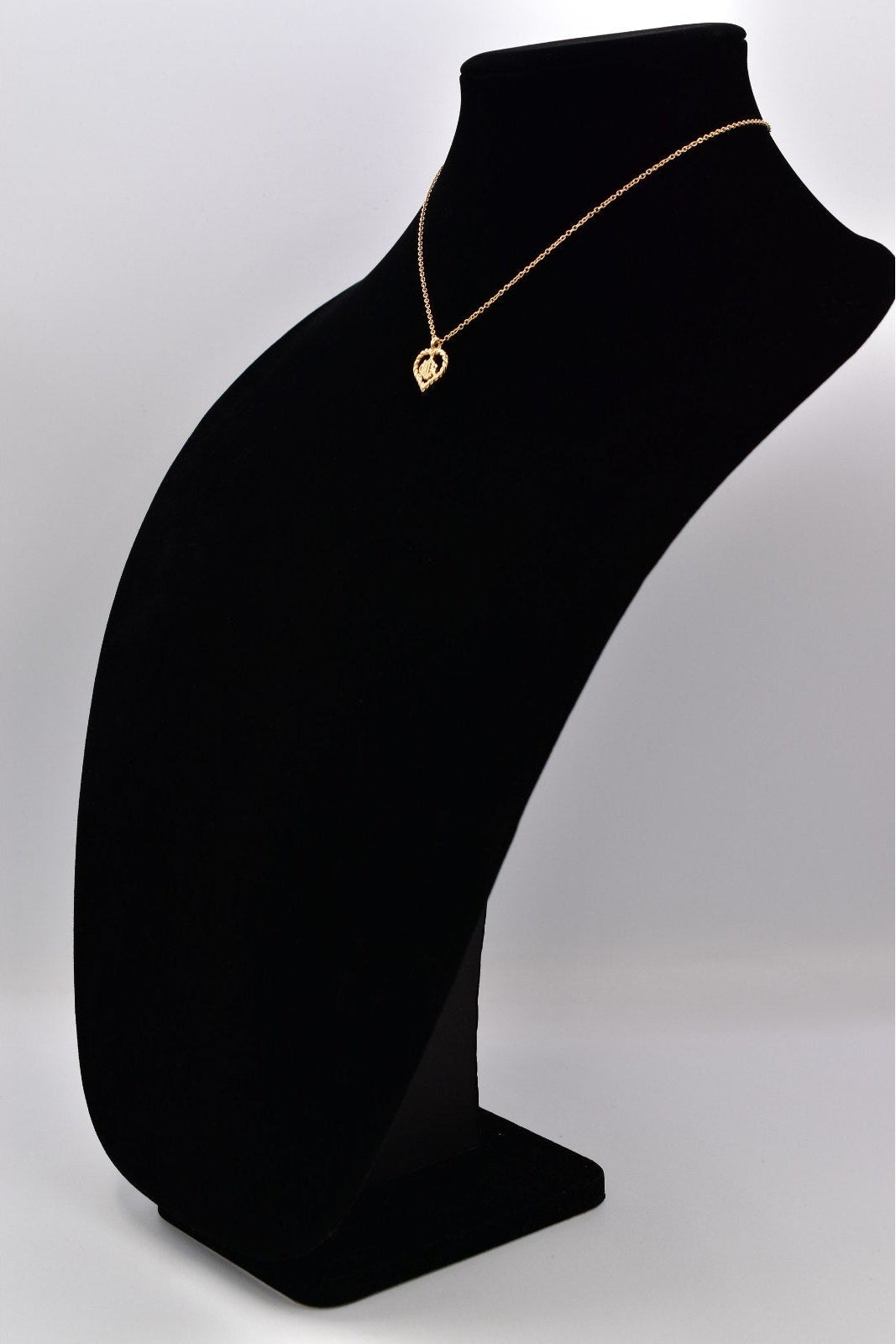 Gold necklace on a black mannequin bust against a white background