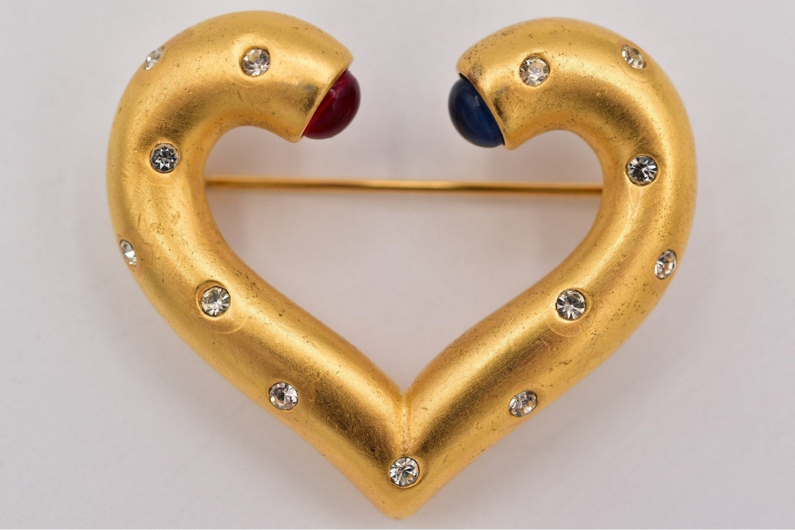 Gold heart-shaped brooch with gemstones on a white background