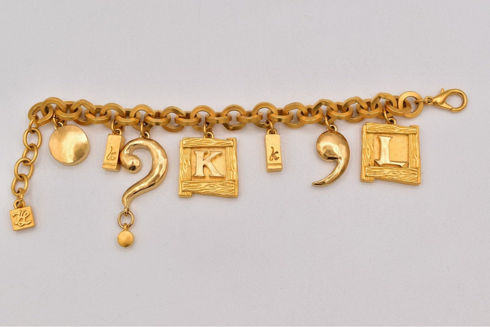 Gold charm bracelet with various charms on a light gray background