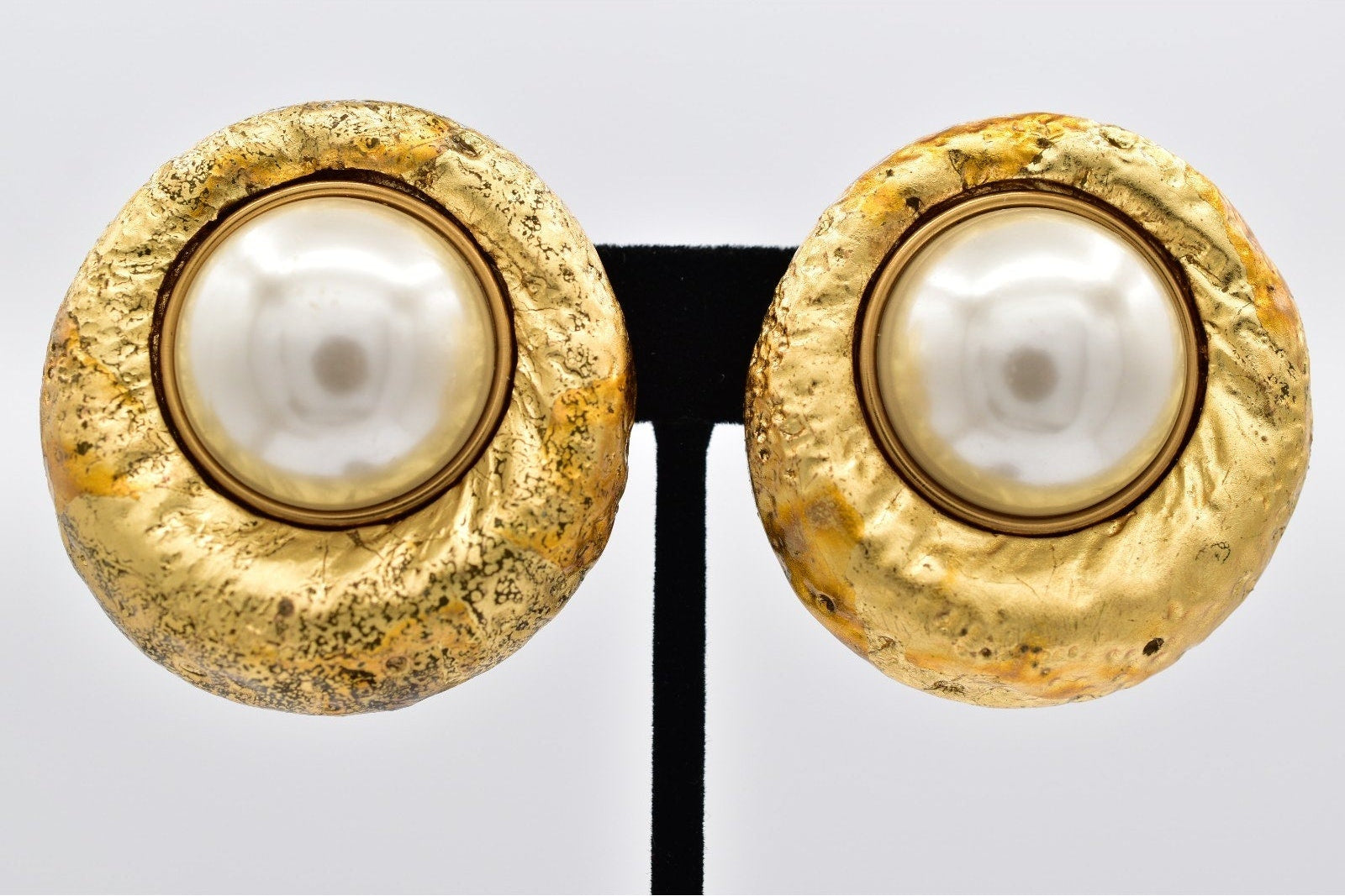 Gold earrings with pearl centers on a white background