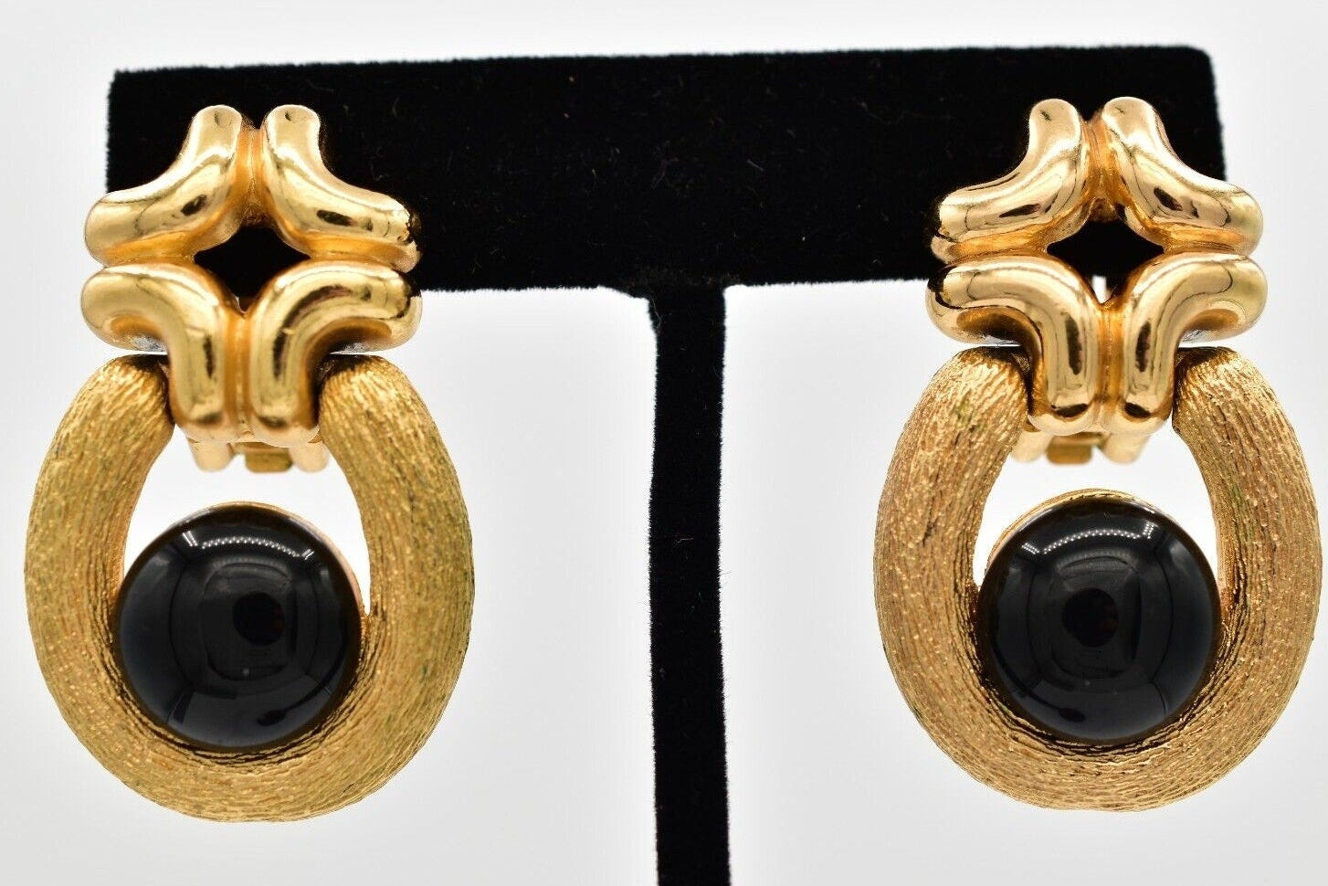 Gold hoop earrings with black centers on a display stand