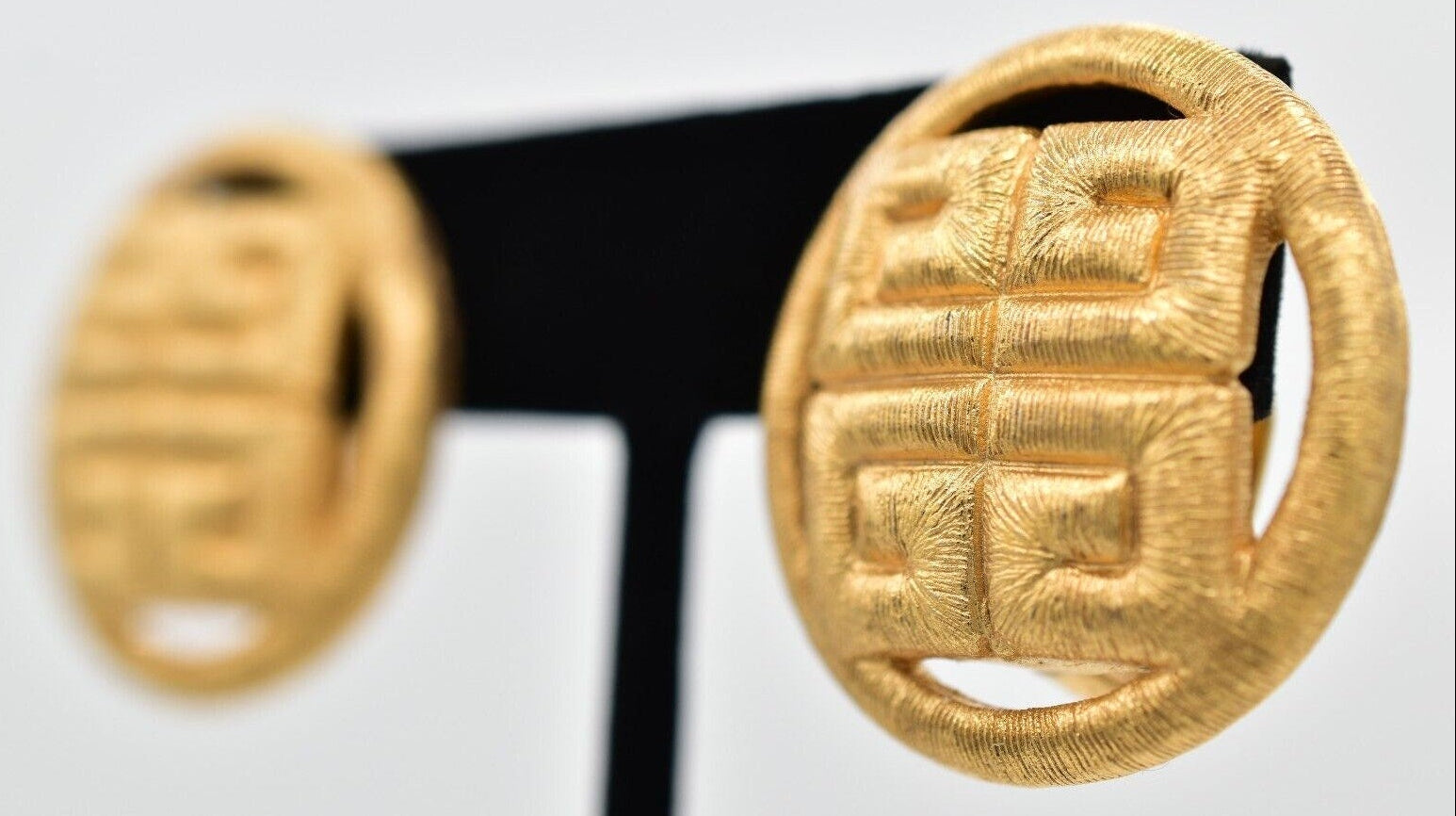 Pair of gold earrings with intricate designs on a white background