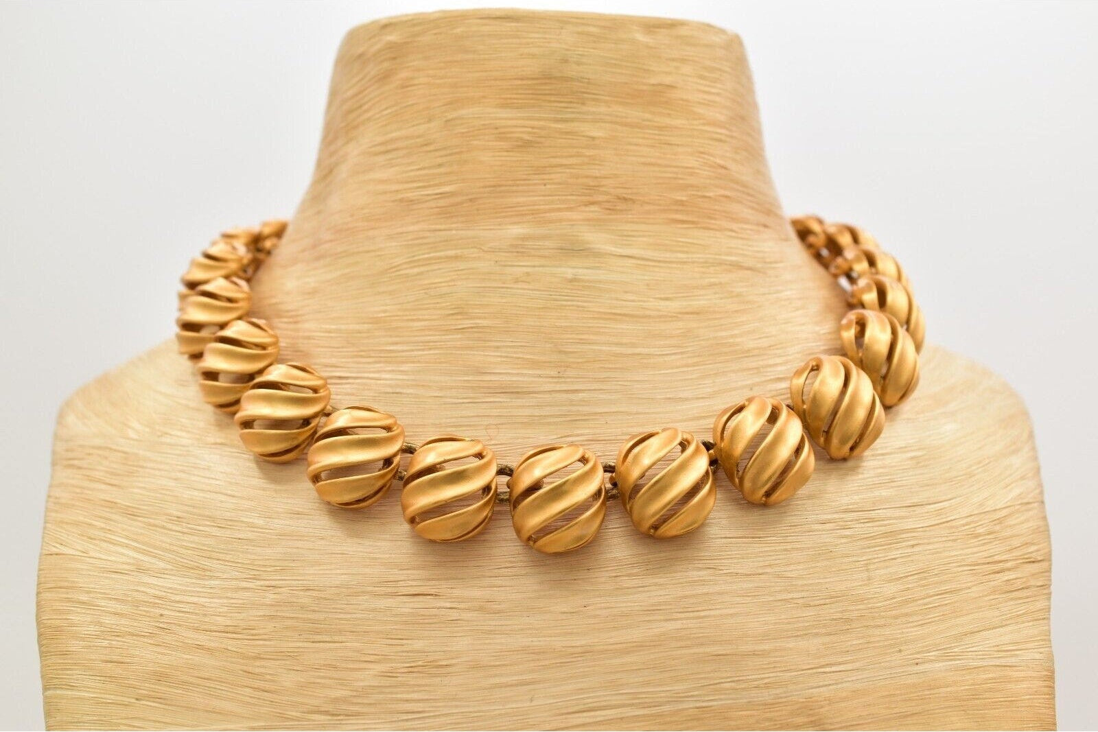 Gold necklace on a wooden mannequin with a white background