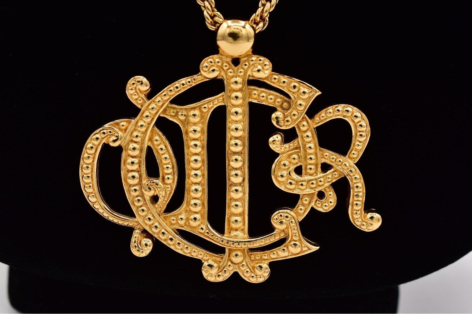 Gold necklace with a decorative pendant on a black background