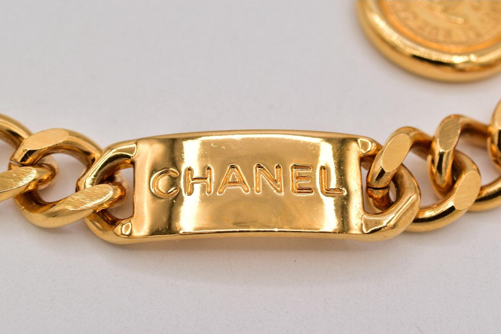 Gold Chanel bracelet on a light gray background