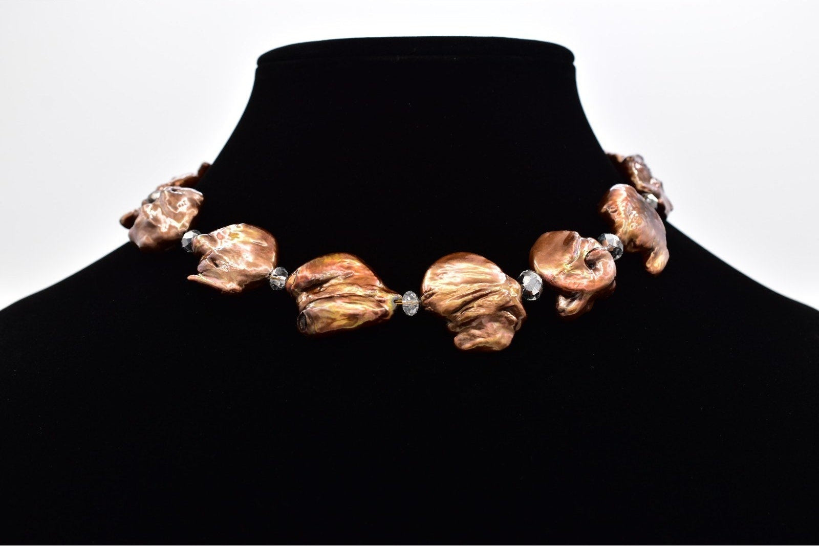 Necklace with large brown beads on a black mannequin against a white background