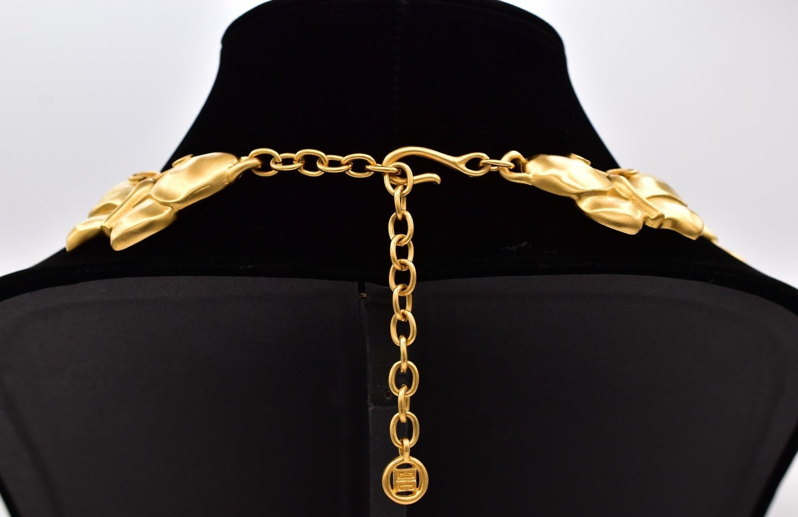 View of the circular 4G hangtag logo on a vintage Givenchy gold tone necklace