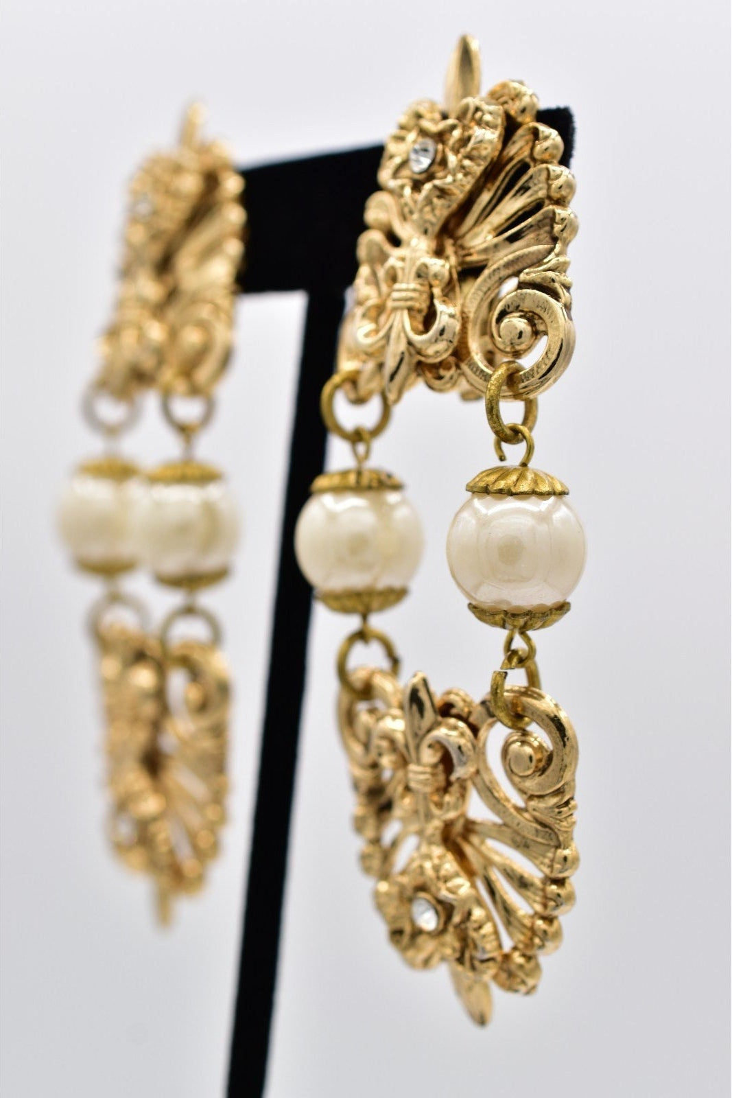 Gold earrings with pearl-like beads on a white background