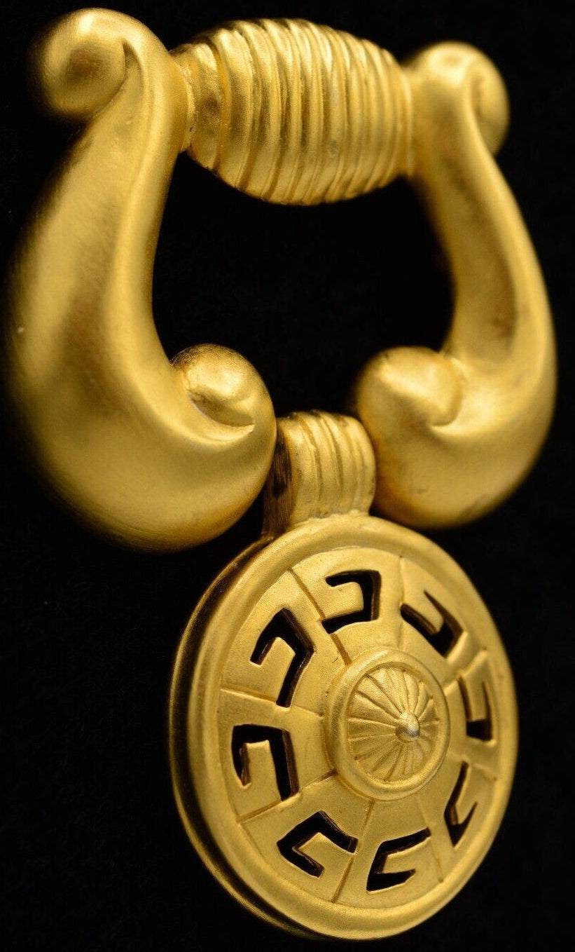 Gold brooch with a doorknocker design on a black background