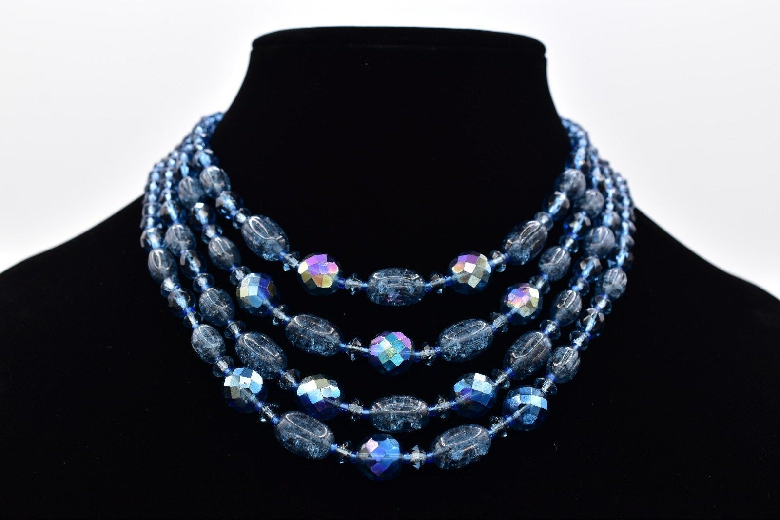 Necklace with blue beads on a black mannequin against a white background