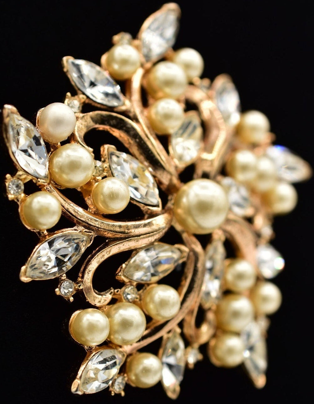 Gold brooch with pearls and crystals on a black background