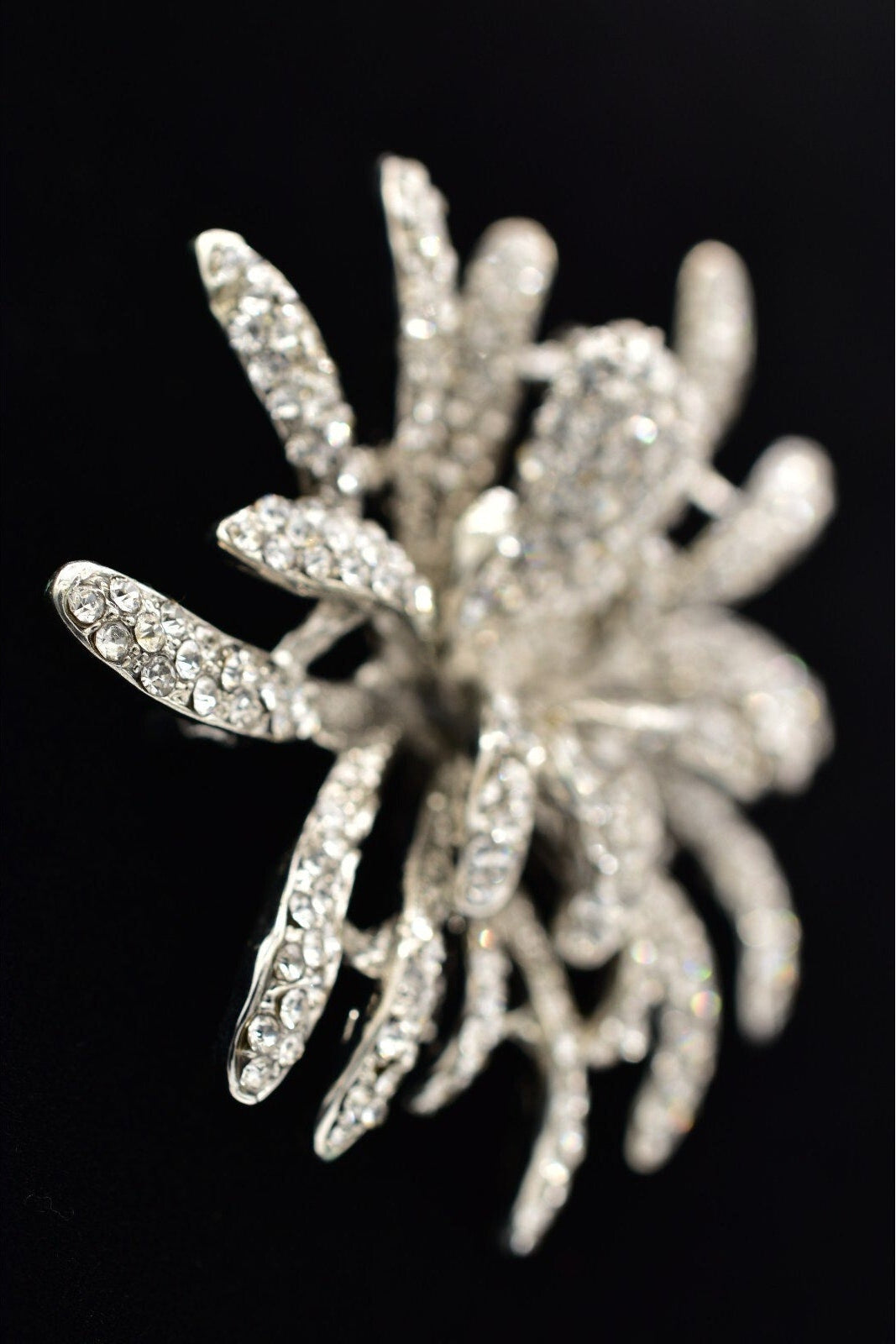 Silver starfish-shaped brooch with rhinestones on a black background
