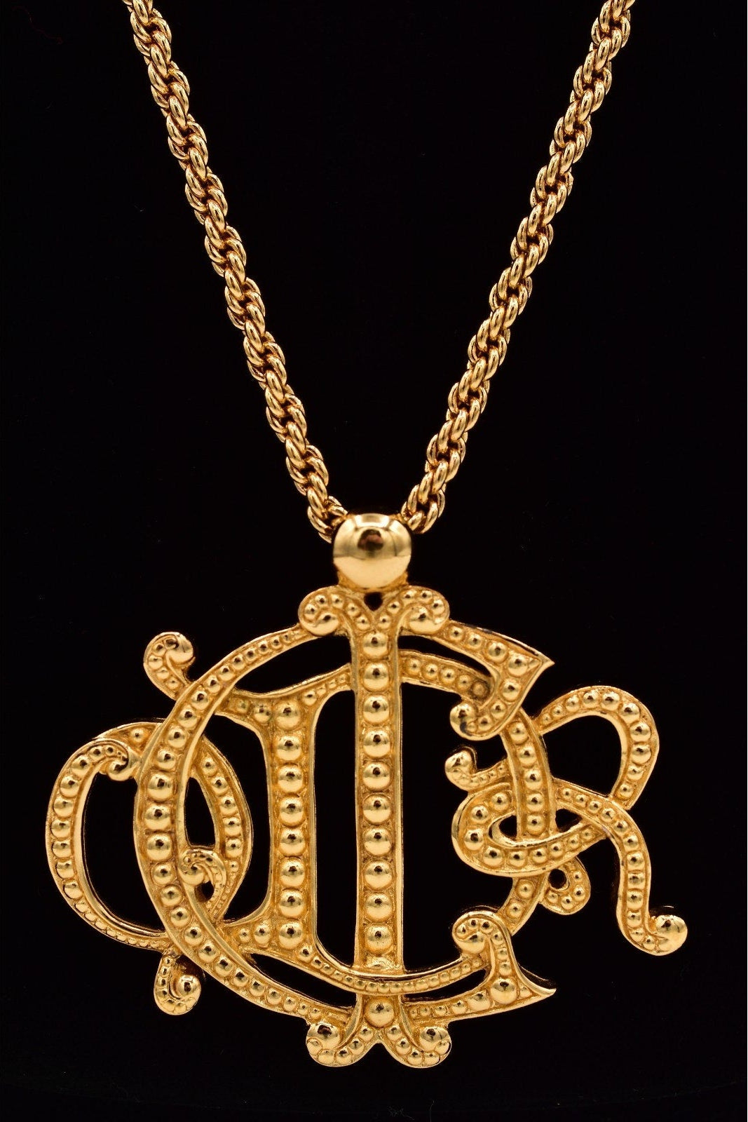 Gold necklace with a decorative pendant on a black background