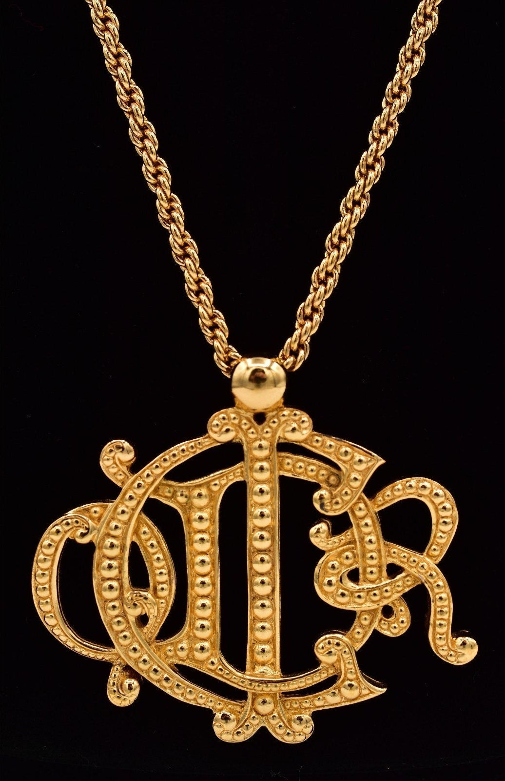 Vintage Christian Dior insignia pendant necklace on a black background