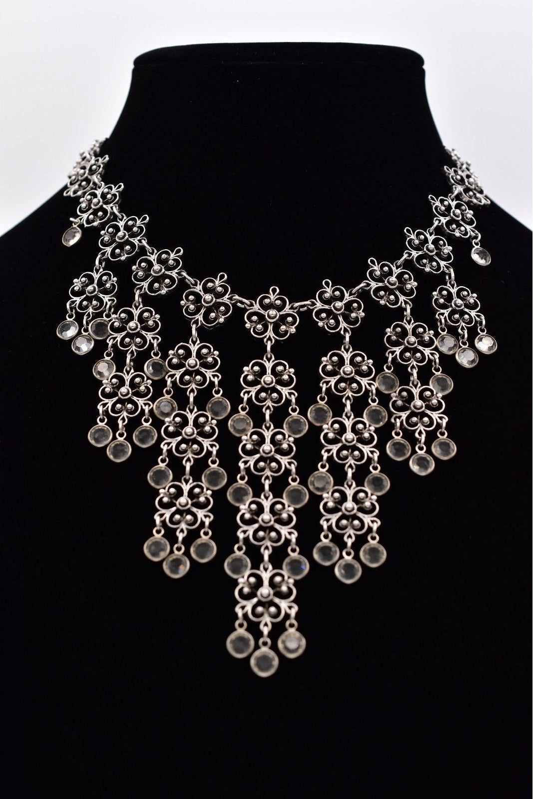 Silver necklace on a black mannequin against a white background