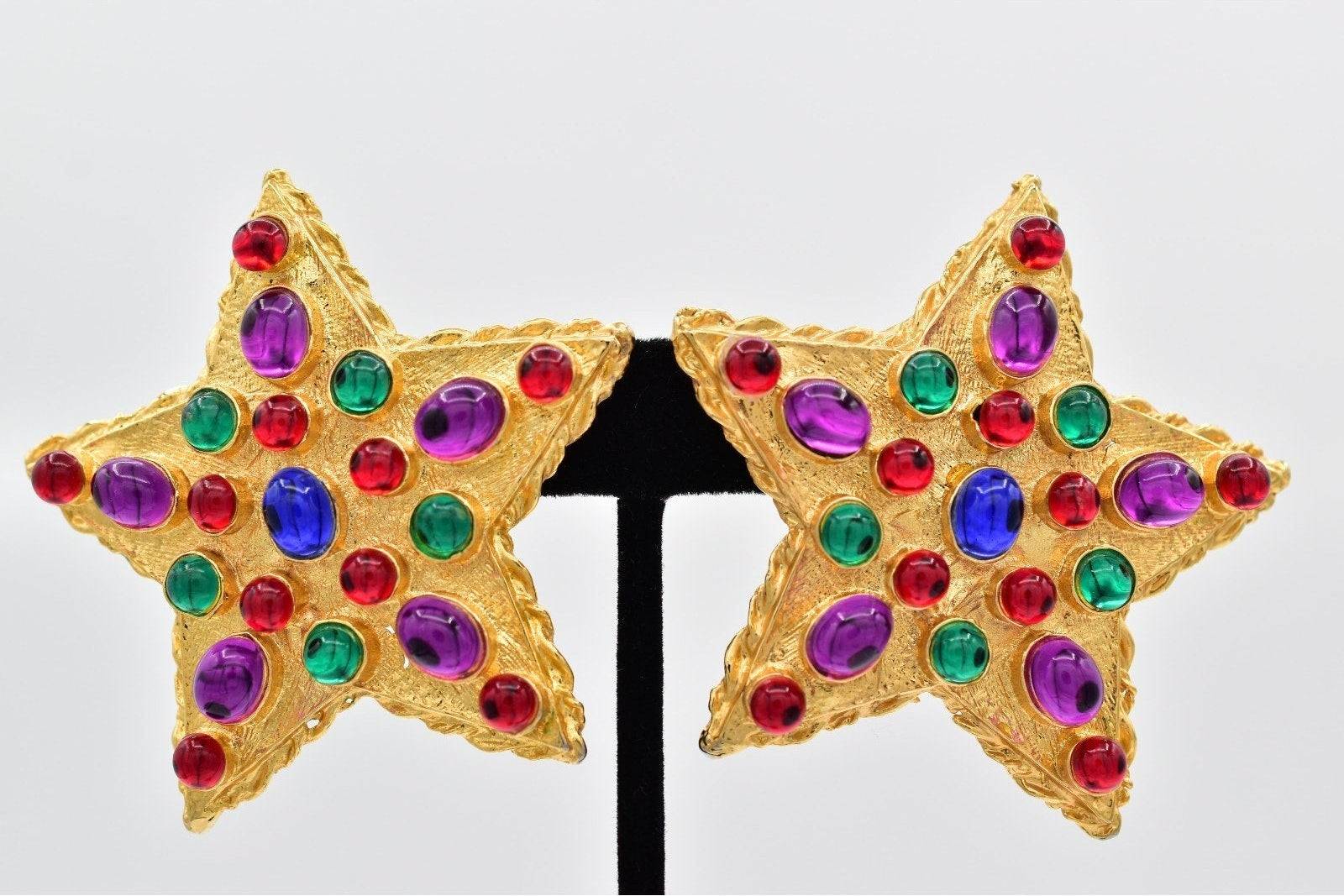 Star-shaped earrings with gold frame and multicolored gemstones on a white background