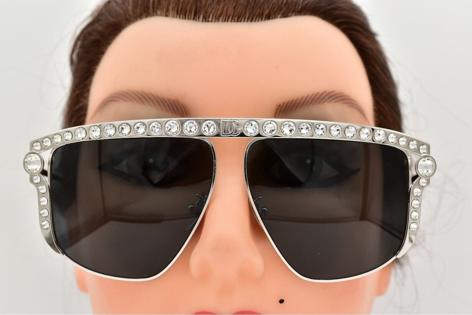 Sunglasses with decorative frame on a mannequin head against a white background