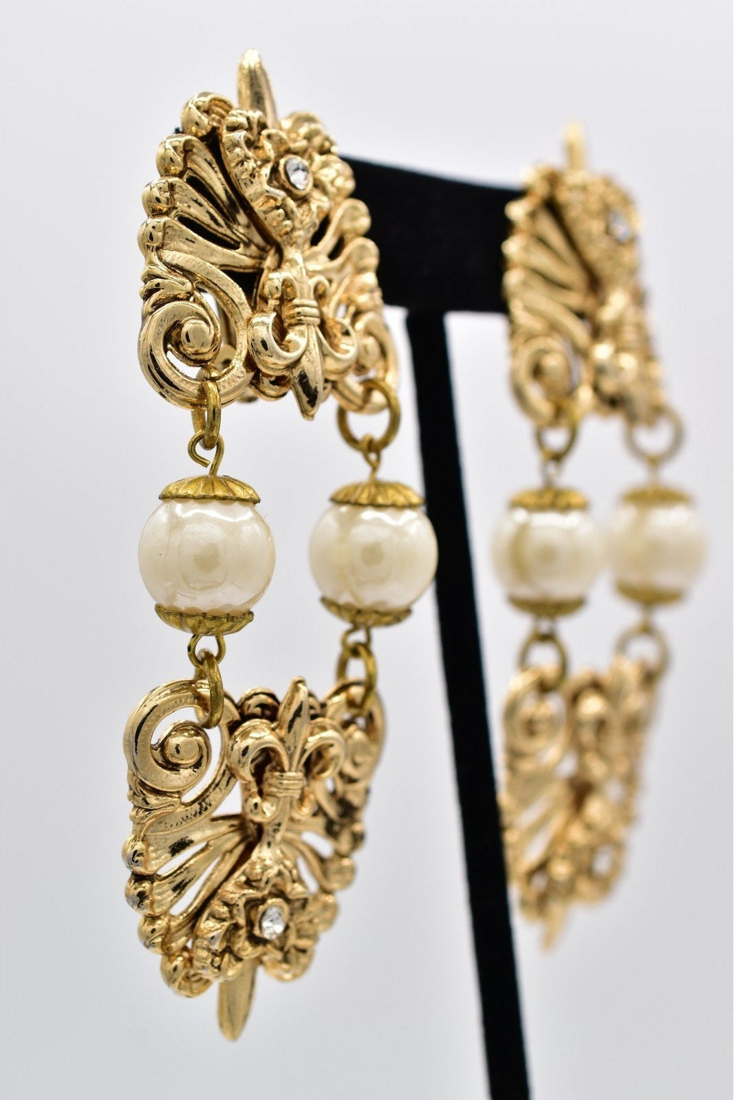 Gold earrings with pearl-like beads on a white background